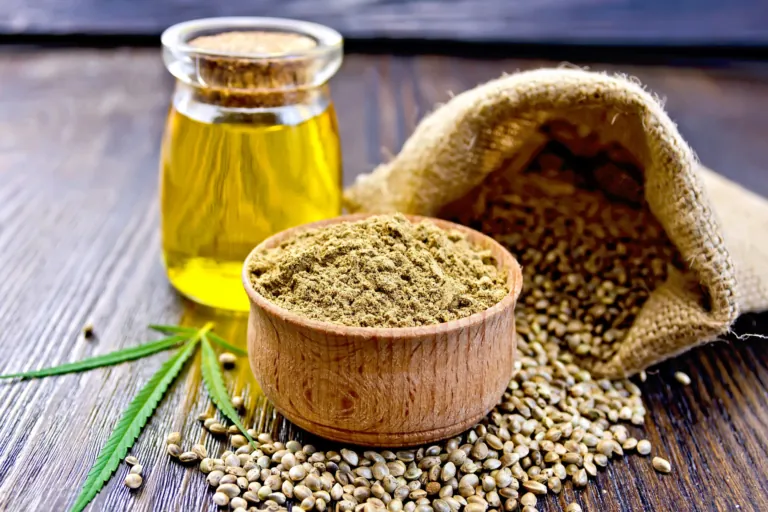 Olejek CBD leżący obok sproszkowanej konopi i jej ziaren